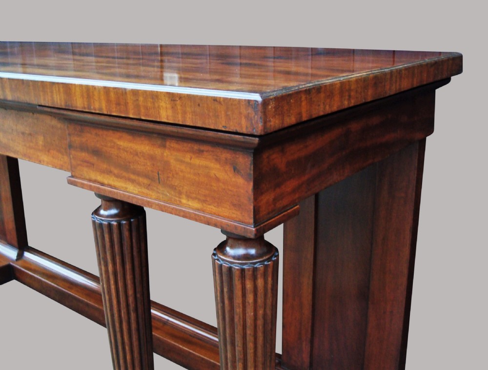 A Regency mahogany serving table featuring a polished rectangular top supported by twin reeded columns on plinth bases. View IX