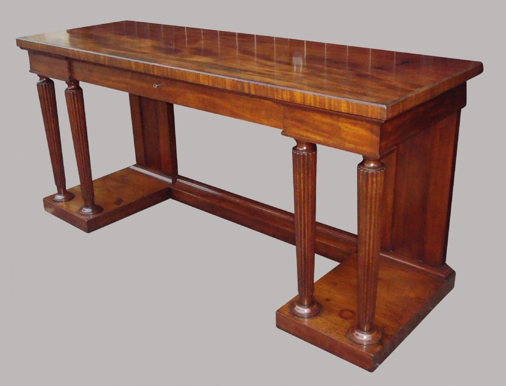 A Regency mahogany serving table featuring a polished rectangular top supported by twin reeded columns on plinth bases. View XI