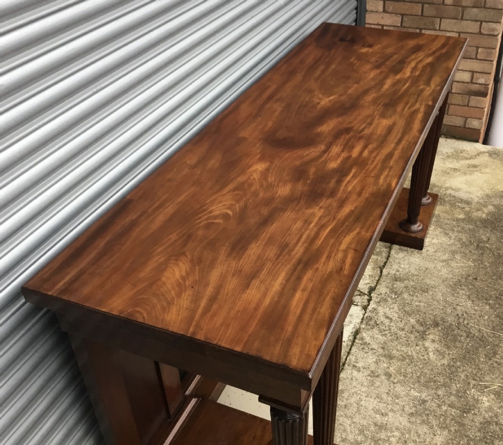 A Regency mahogany serving table featuring a polished rectangular top supported by twin reeded columns on plinth bases. View XV