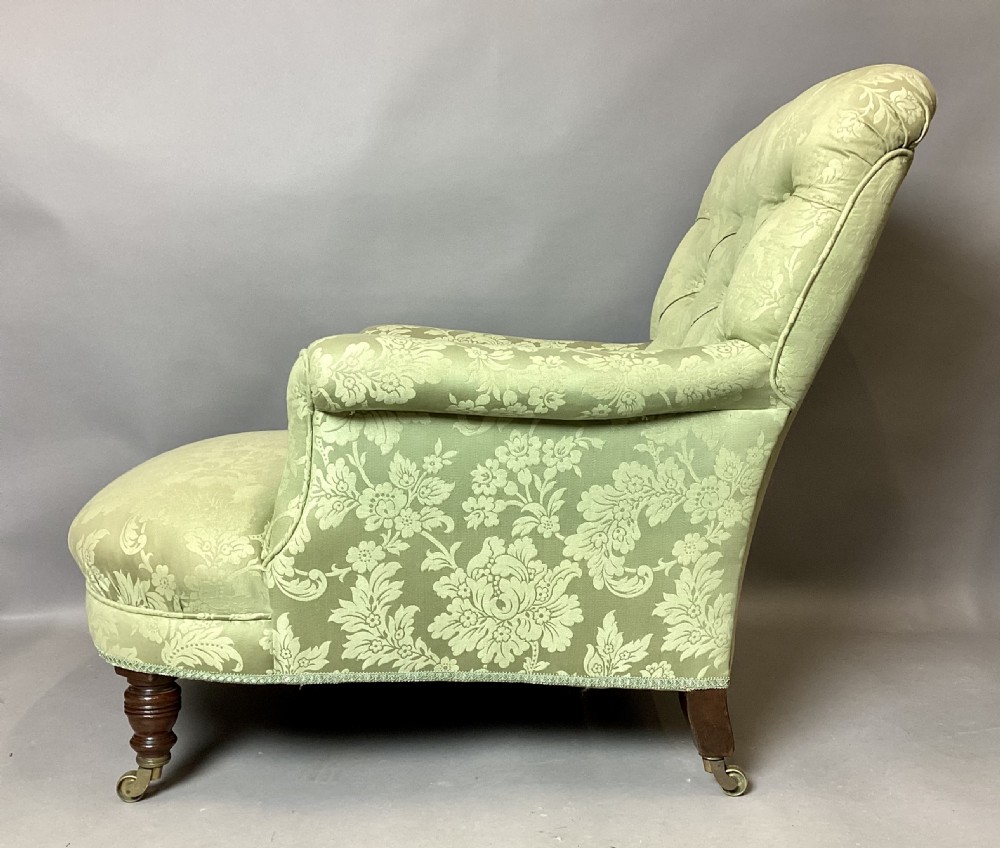 A nineteenth-century Victorian armchair upholstered in sage green floral fabric with a deep button-tufted backrest and turned wooden legs on brass castors. View III