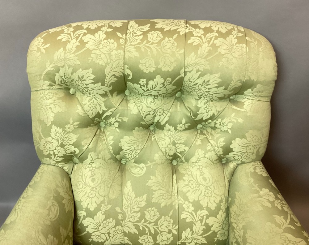 A nineteenth-century Victorian armchair upholstered in sage green floral fabric with a deep button-tufted backrest and turned wooden legs on brass castors. View XVI