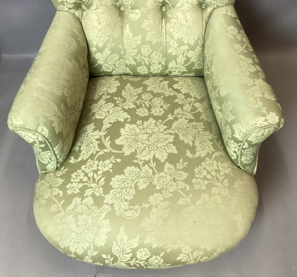 A nineteenth-century Victorian armchair upholstered in sage green floral fabric with a deep button-tufted backrest and turned wooden legs on brass castors. View XVII