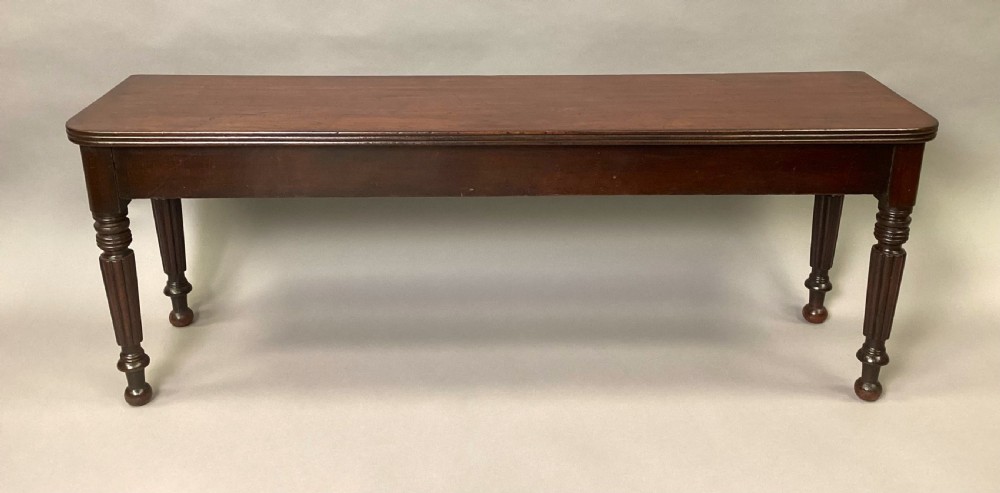 A long Regency mahogany hall bench featuring turned reeded legs, a rectangular solid top with rounded corners, and a polished dark timber finish. View II