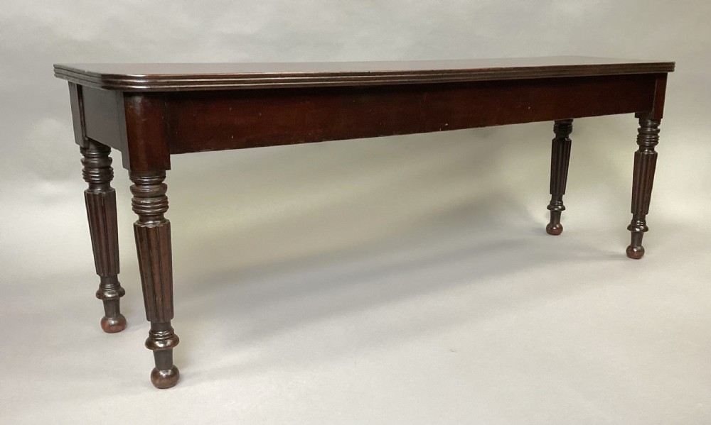 A long Regency mahogany hall bench featuring turned reeded legs, a rectangular solid top with rounded corners, and a polished dark timber finish. View IX