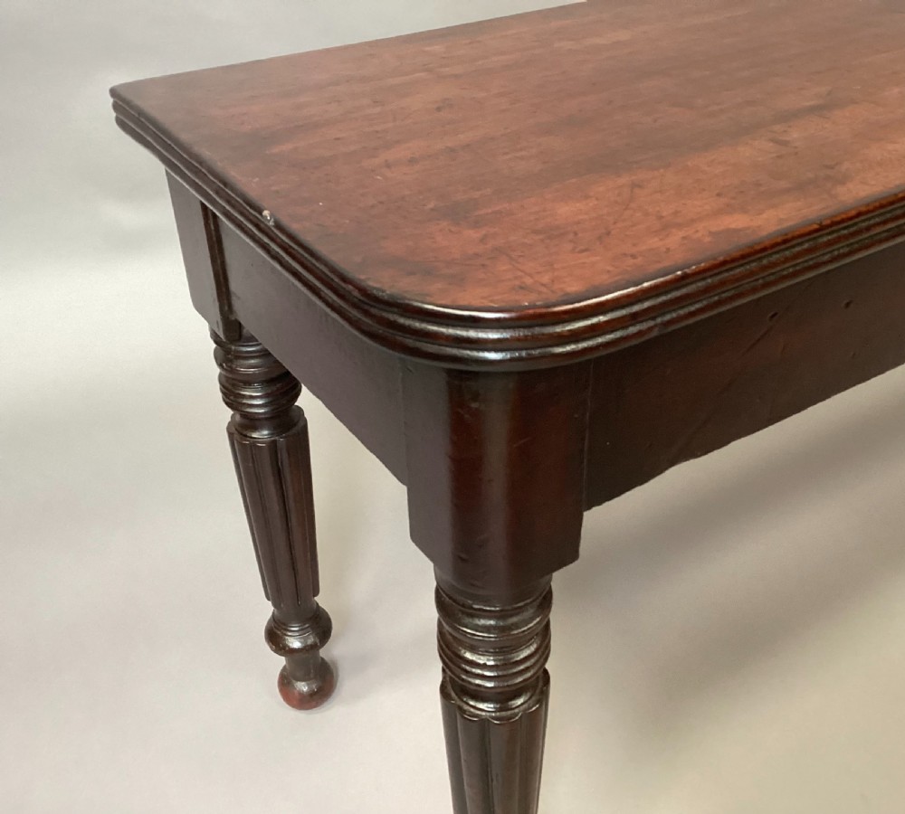 A long Regency mahogany hall bench featuring turned reeded legs, a rectangular solid top with rounded corners, and a polished dark timber finish. View XII