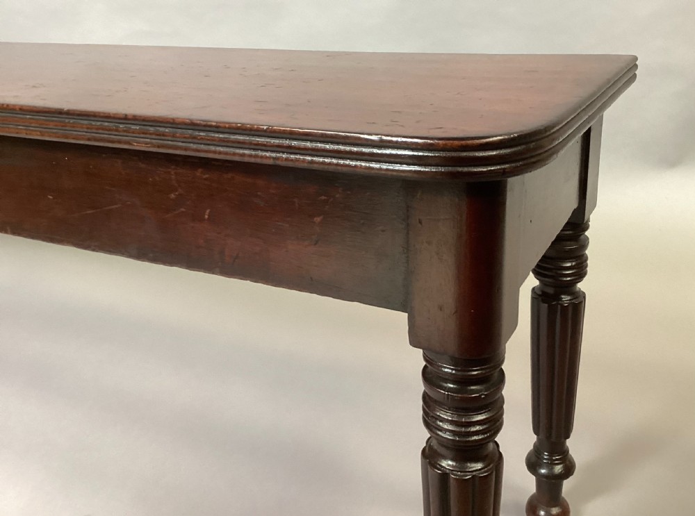 A long Regency mahogany hall bench featuring turned reeded legs, a rectangular solid top with rounded corners, and a polished dark timber finish. View XIII