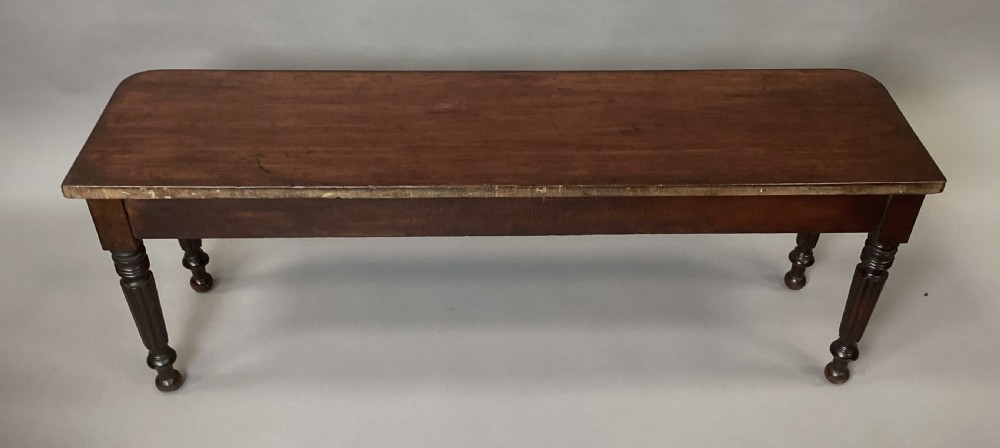 A long Regency mahogany hall bench featuring turned reeded legs, a rectangular solid top with rounded corners, and a polished dark timber finish. View XV