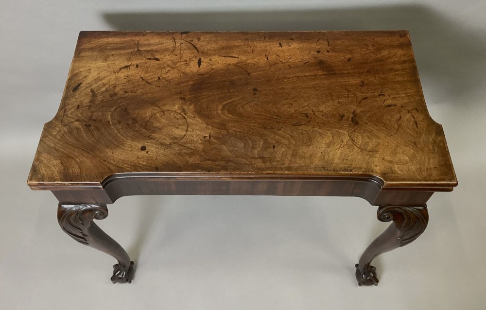 A George II mahogany fold-over tea table featuring carved cabriole legs with acanthus knees and claw-and-ball feet. View XVII