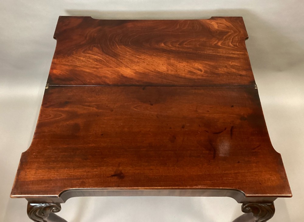 A George II mahogany fold-over tea table featuring carved cabriole legs with acanthus knees and claw-and-ball feet. View XX