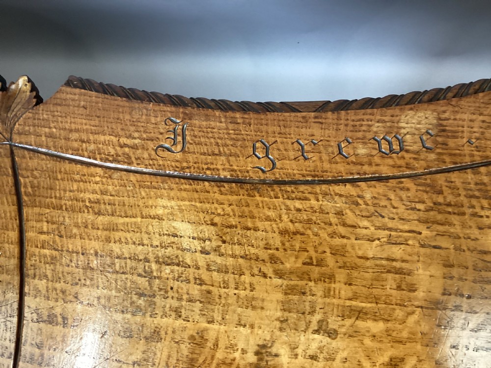 A Regency figured oak occasional table featuring carved acanthus corners, a rope-twist border, incised lettering detail, a turned central stem, and carved legs on castors. View VII