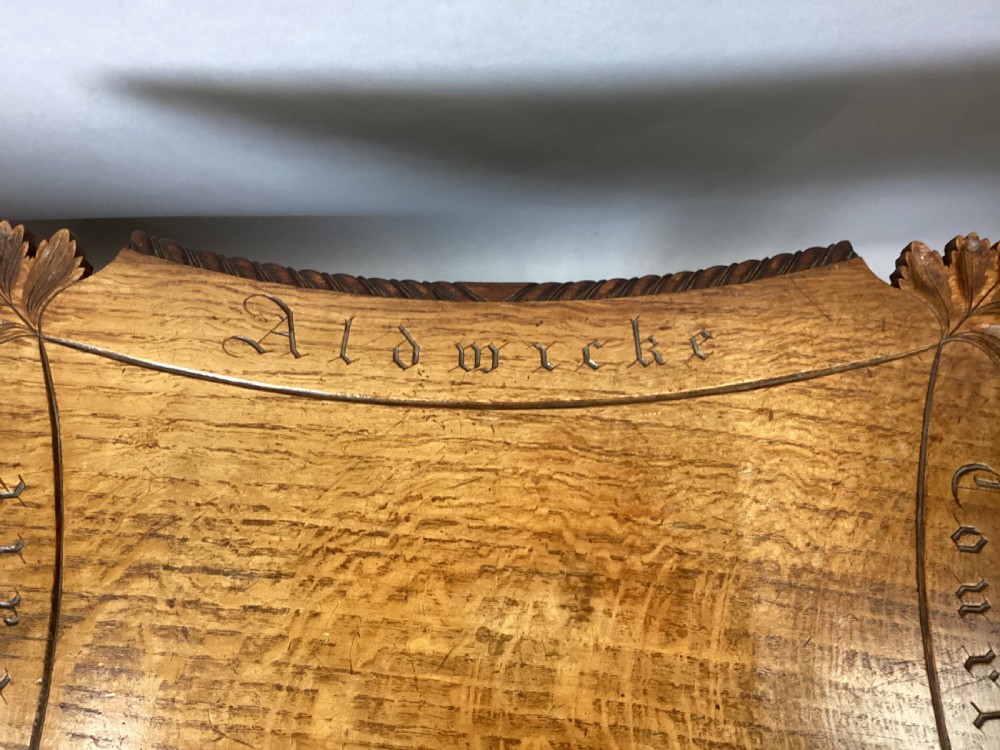 A Regency figured oak occasional table featuring carved acanthus corners, a rope-twist border, incised lettering detail, a turned central stem, and carved legs on castors. View IX