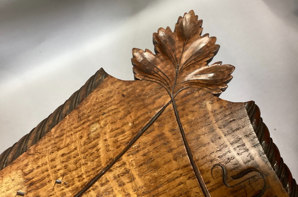 A Regency figured oak occasional table featuring carved acanthus corners, a rope-twist border, incised lettering detail, a turned central stem, and carved legs on castors. View XI