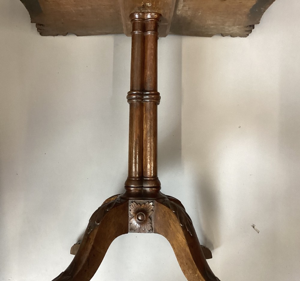 A Regency figured oak occasional table featuring carved acanthus corners, a rope-twist border, incised lettering detail, a turned central stem, and carved legs on castors. View XVI