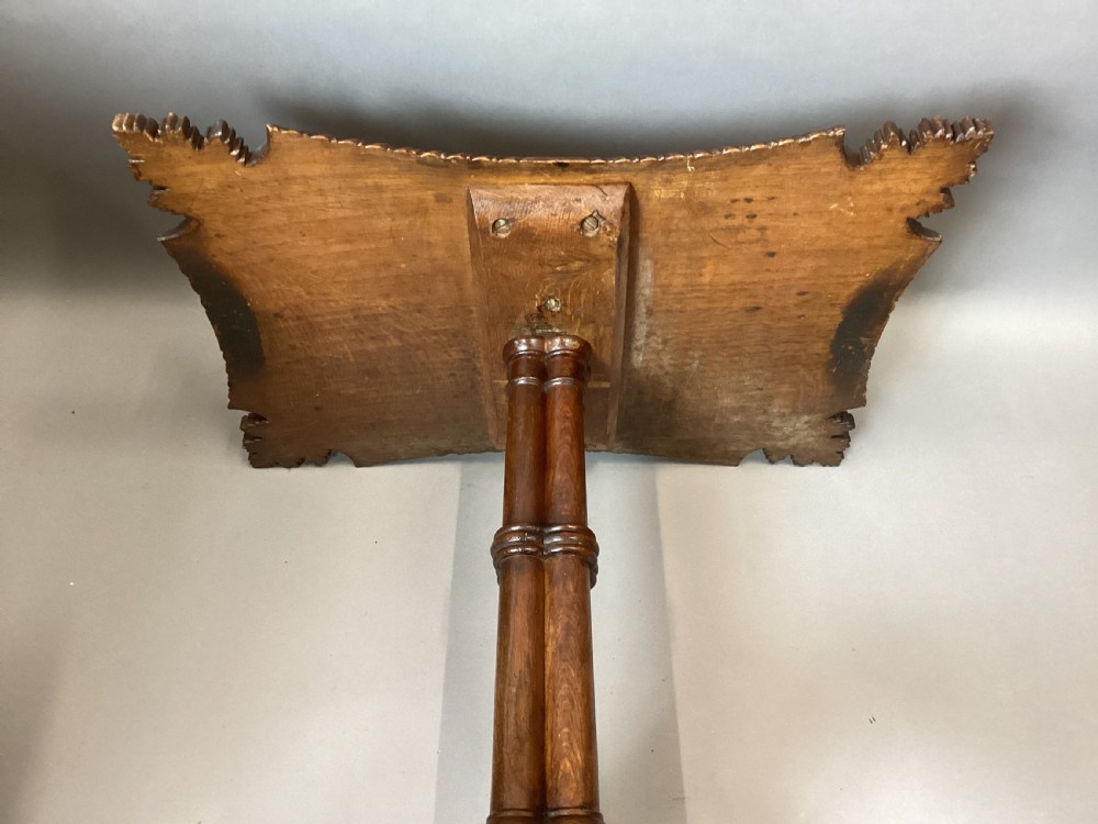 A Regency figured oak occasional table featuring carved acanthus corners, a rope-twist border, incised lettering detail, a turned central stem, and carved legs on castors. View XX