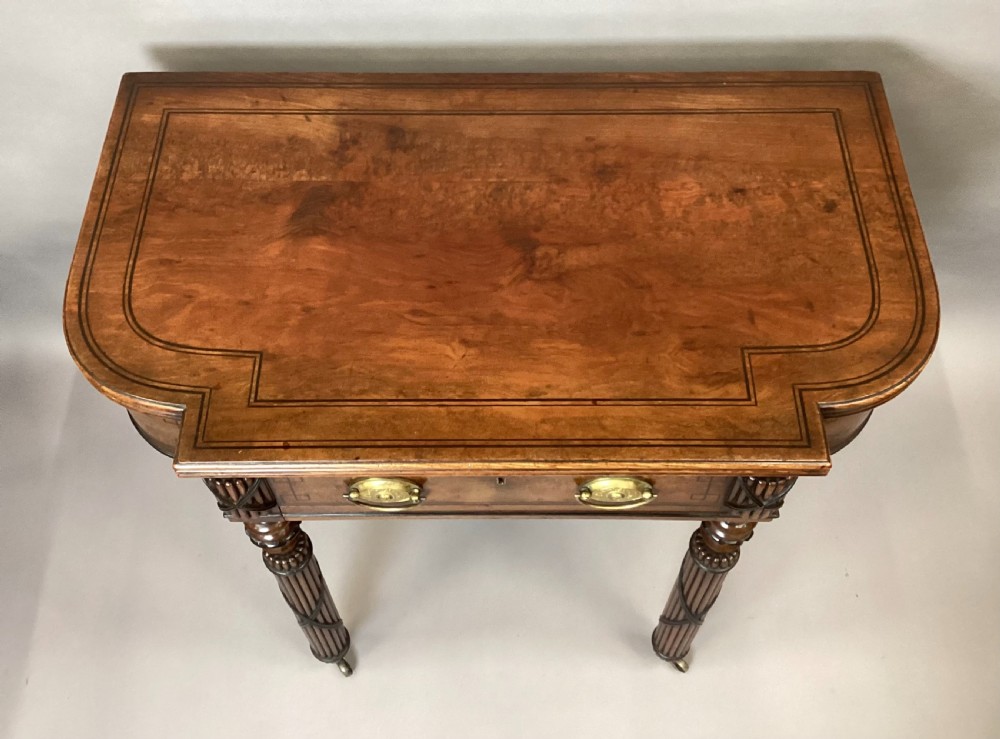 A Regency mahogany side table featuring ebony inlay details, turned spiral legs with brass castors, and a front drawer with circular brass handles. View IV