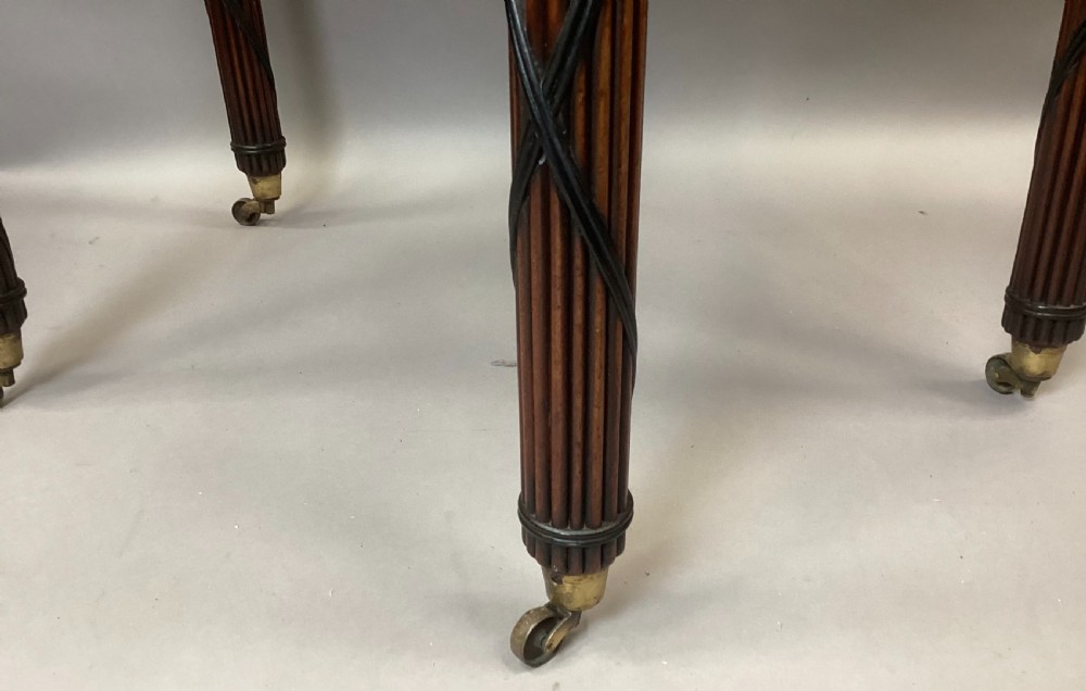 A Regency mahogany side table featuring ebony inlay details, turned spiral legs with brass castors, and a front drawer with circular brass handles. View X