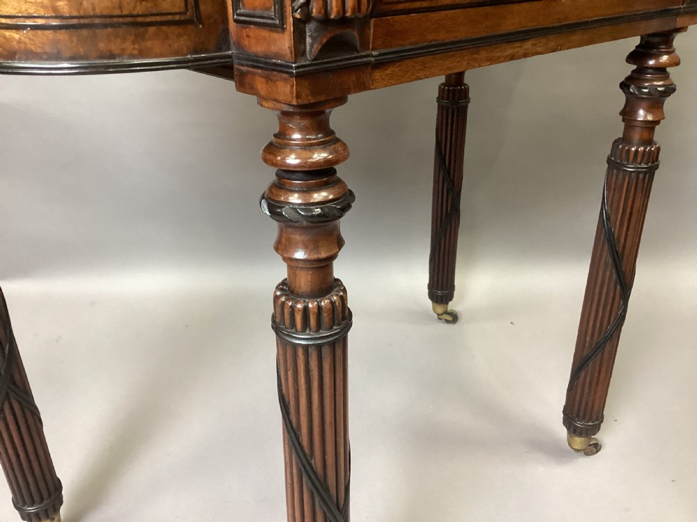 A Regency mahogany side table featuring ebony inlay details, turned spiral legs with brass castors, and a front drawer with circular brass handles. View XII