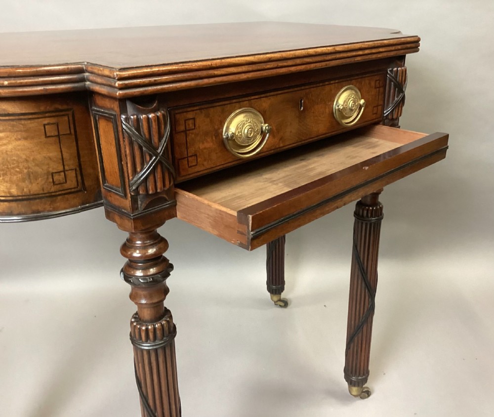 A Regency mahogany side table featuring ebony inlay details, turned spiral legs with brass castors, and a front drawer with circular brass handles. View XV