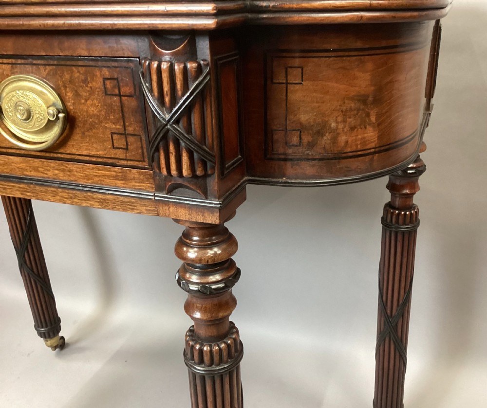 A Regency mahogany side table featuring ebony inlay details, turned spiral legs with brass castors, and a front drawer with circular brass handles. View XVII