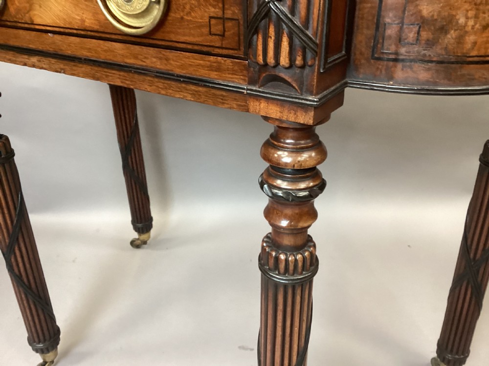 A Regency mahogany side table featuring ebony inlay details, turned spiral legs with brass castors, and a front drawer with circular brass handles. View XVIII
