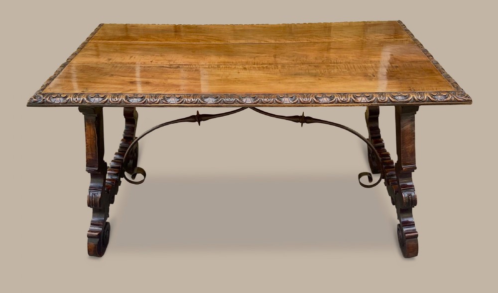 An 18th-century Spanish walnut and fruitwood centre table featuring carved trestle supports, decorative edge moulding, and wrought iron stretchers. View II