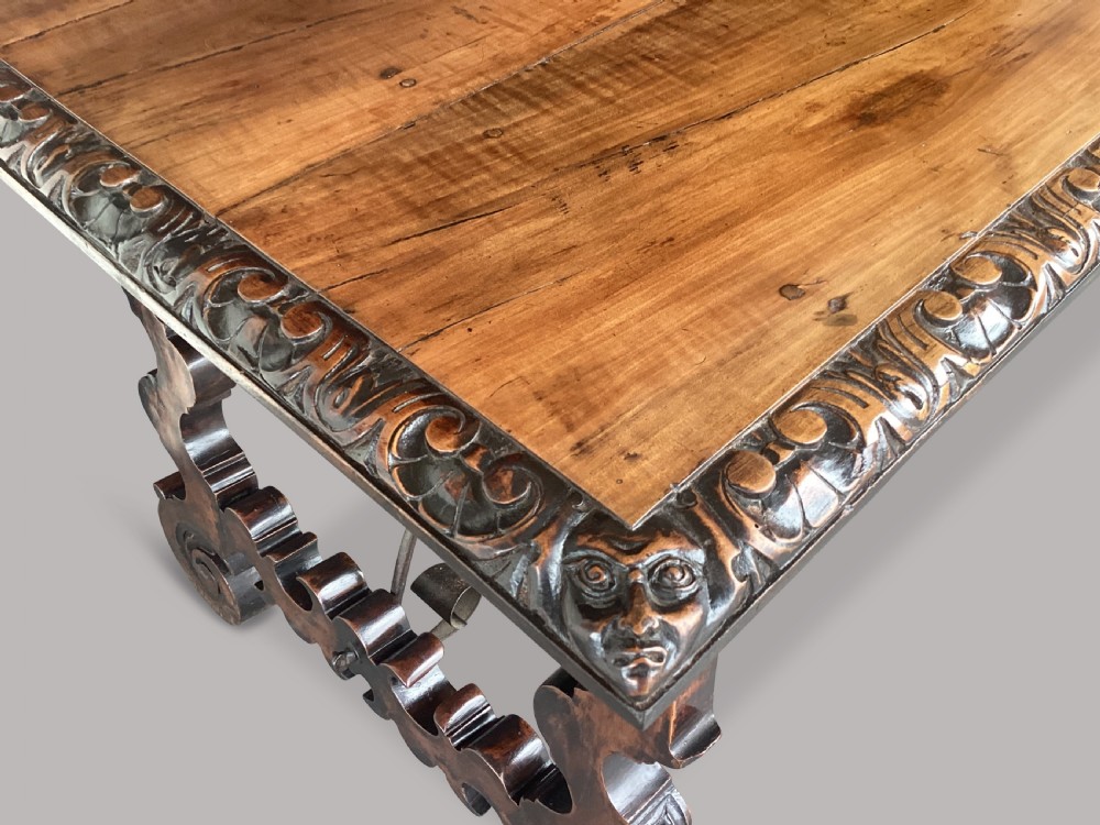 An 18th-century Spanish walnut and fruitwood centre table featuring carved trestle supports, decorative edge moulding, and wrought iron stretchers. View III
