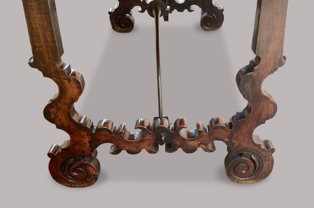 An 18th-century Spanish walnut and fruitwood centre table featuring carved trestle supports, decorative edge moulding, and wrought iron stretchers. View IV