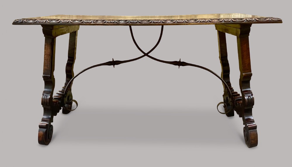 An 18th-century Spanish walnut and fruitwood centre table featuring carved trestle supports, decorative edge moulding, and wrought iron stretchers. View XII