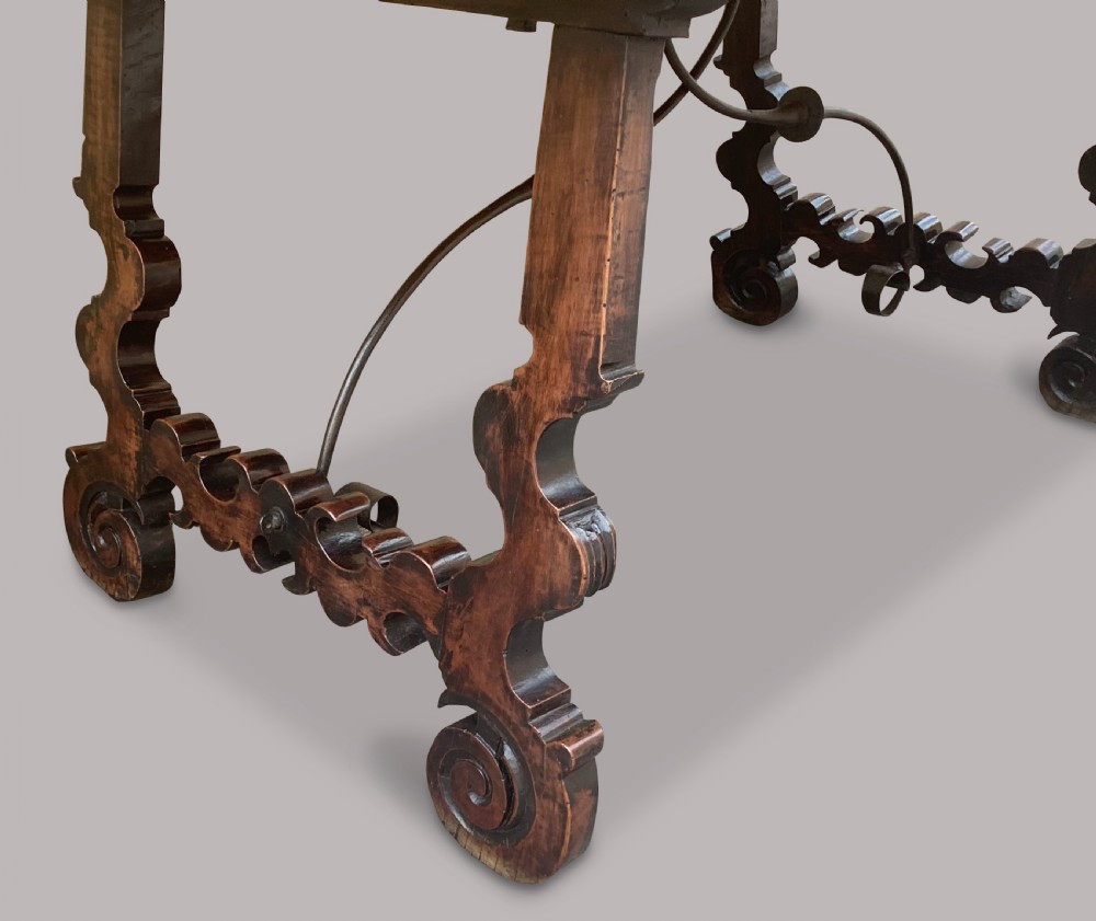 An 18th-century Spanish walnut and fruitwood centre table featuring carved trestle supports, decorative edge moulding, and wrought iron stretchers. View XIII