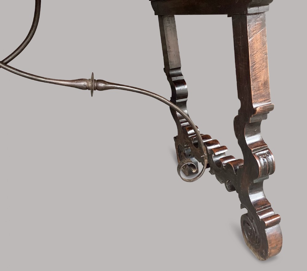 An 18th-century Spanish walnut and fruitwood centre table featuring carved trestle supports, decorative edge moulding, and wrought iron stretchers. View XIV