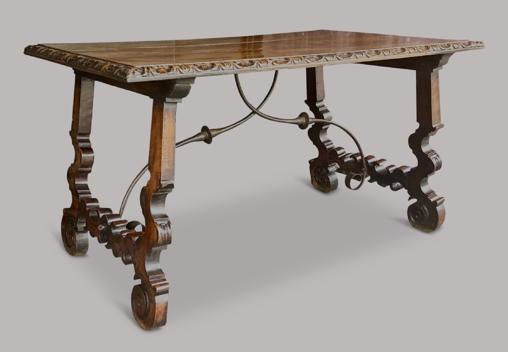 An 18th-century Spanish walnut and fruitwood centre table featuring carved trestle supports, decorative edge moulding, and wrought iron stretchers. View XV