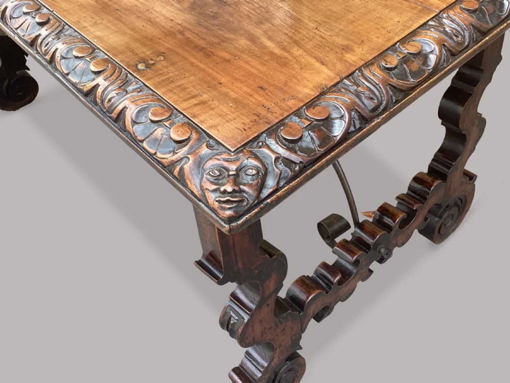An 18th-century Spanish walnut and fruitwood centre table featuring carved trestle supports, decorative edge moulding, and wrought iron stretchers. View XXII