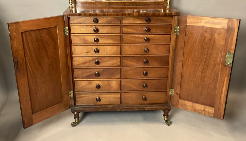 A Regency figured mahogany side cabinet with a top mirror shelf supported by brass spiral columns and topped with a brass gallery. View II