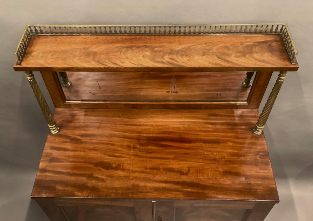 A Regency figured mahogany side cabinet with a top mirror shelf supported by brass spiral columns and topped with a brass gallery. View VI