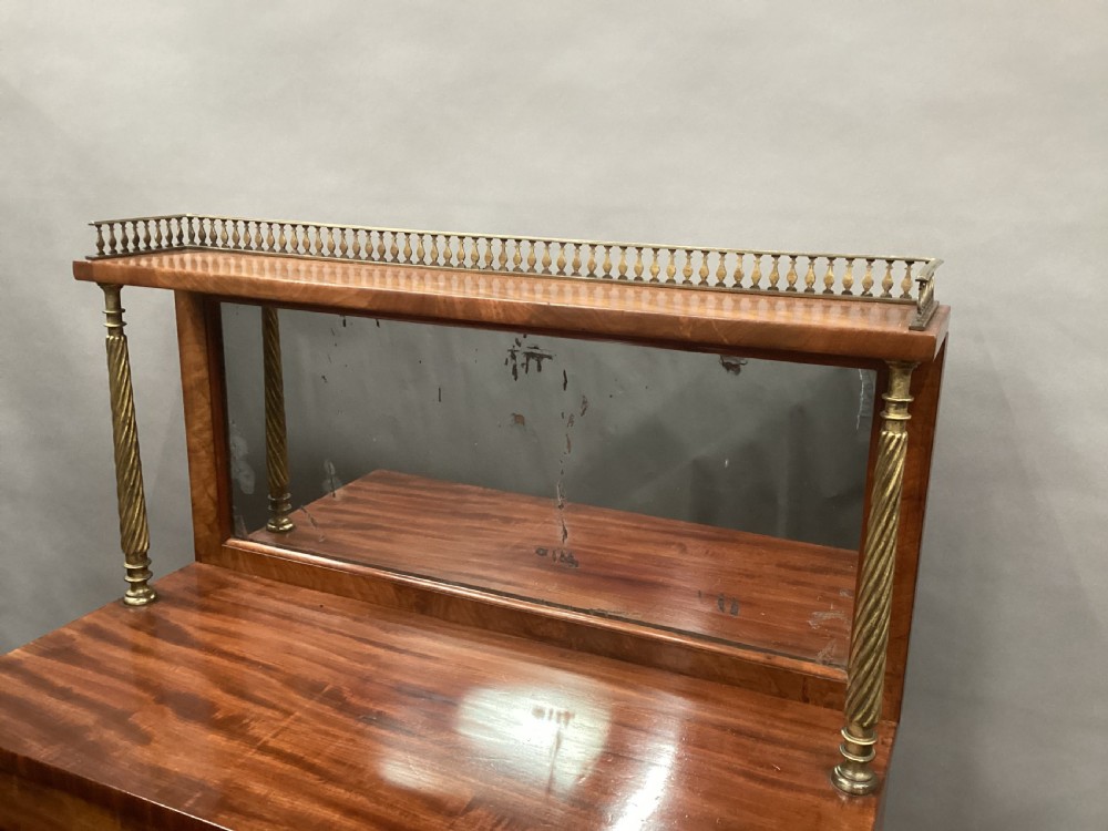 A Regency figured mahogany side cabinet with a top mirror shelf supported by brass spiral columns and topped with a brass gallery. View IX
