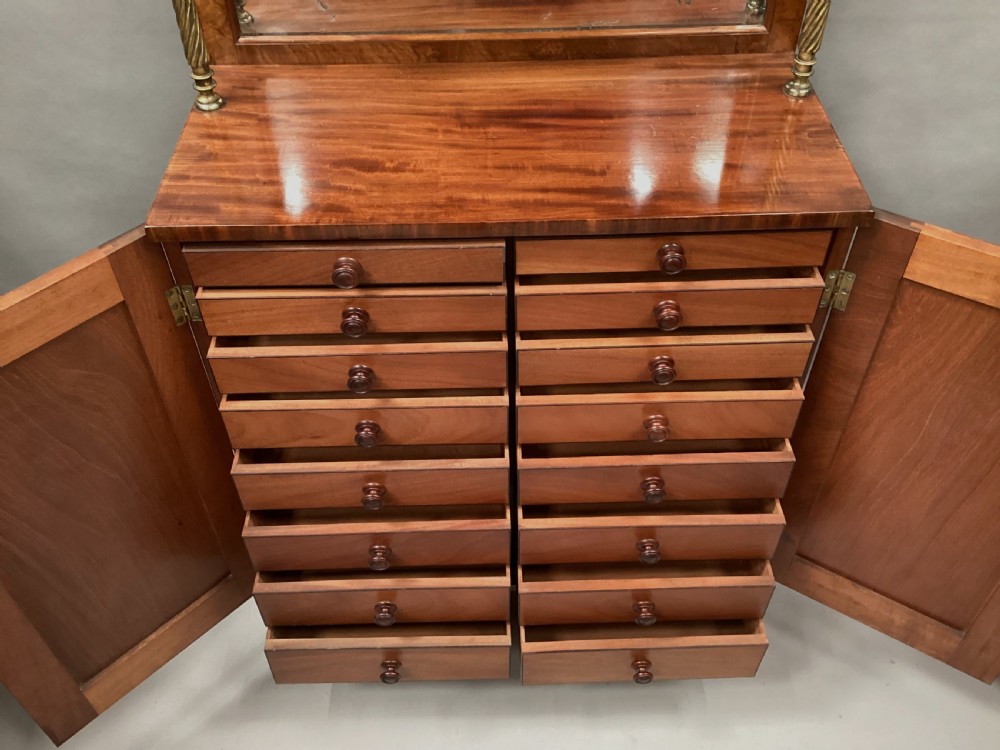 A Regency figured mahogany side cabinet with a top mirror shelf supported by brass spiral columns and topped with a brass gallery. View XII