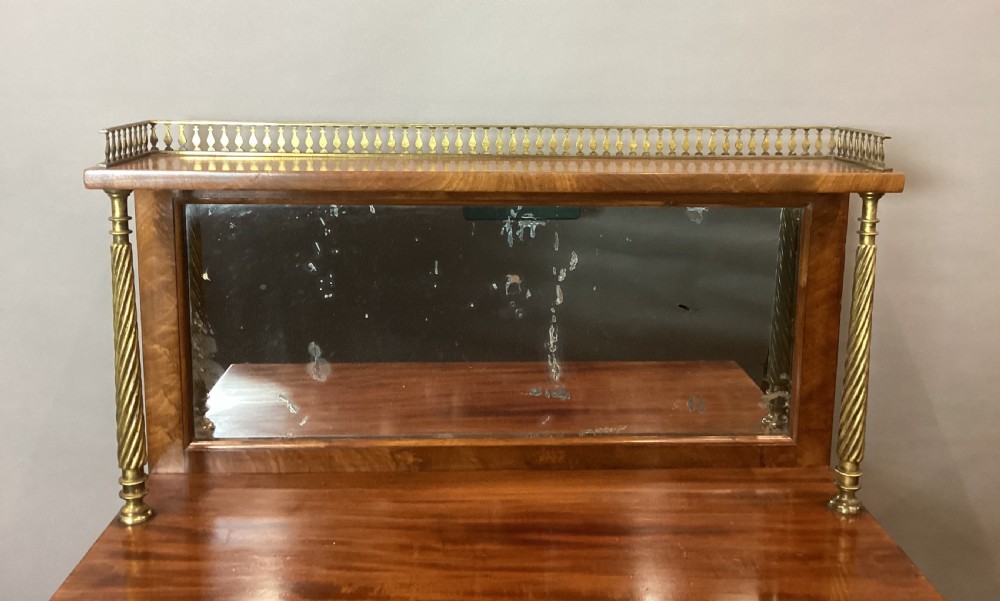 A Regency figured mahogany side cabinet with a top mirror shelf supported by brass spiral columns and topped with a brass gallery. View XVI