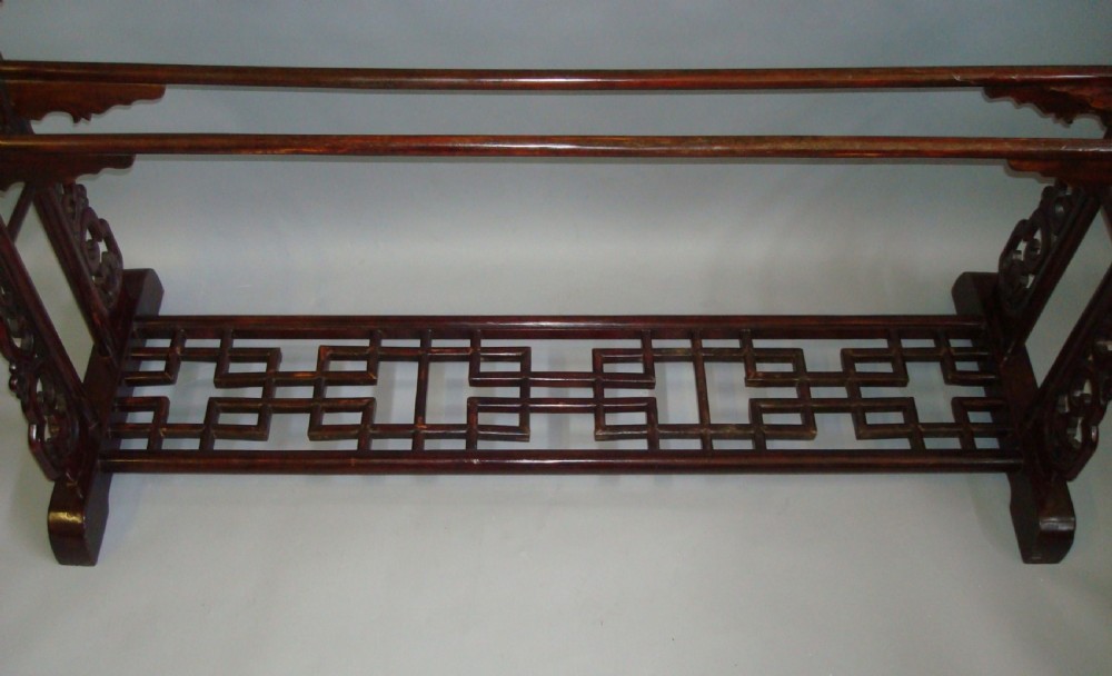 A large nineteenth-century Chinese dark red lacquered wooden robe stand featuring extended top rails, carved decorative spandrels, and a lattice bottom base. View V