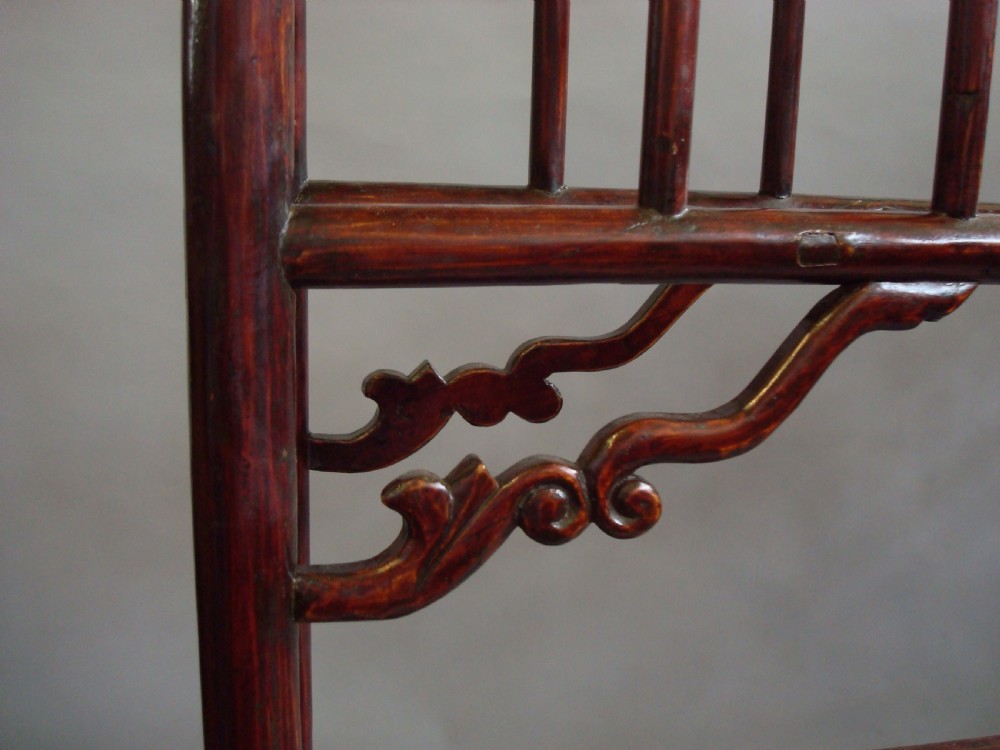A large nineteenth-century Chinese dark red lacquered wooden robe stand featuring extended top rails, carved decorative spandrels, and a lattice bottom base. View VII