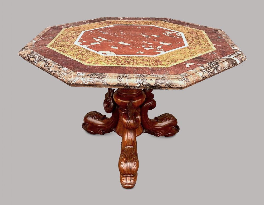 An octagonal 19th-century centre table with a geometric inlaid specimen marble top supported on a carved walnut pedestal base with scroll feet. View V