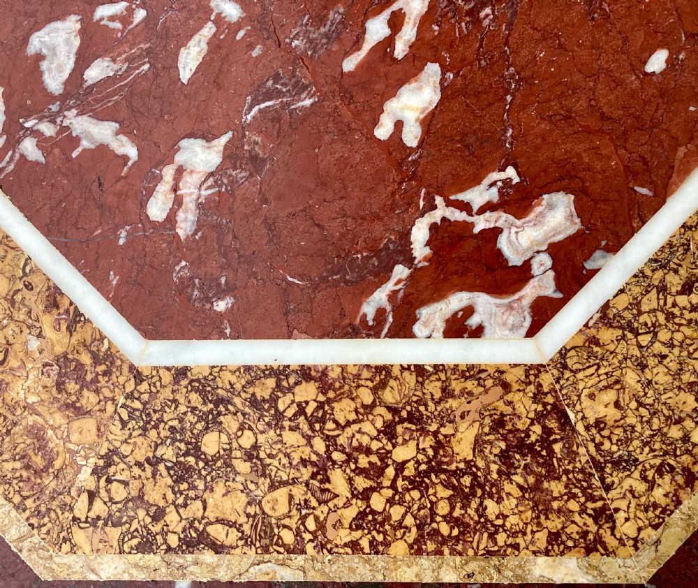 An octagonal 19th-century centre table with a geometric inlaid specimen marble top supported on a carved walnut pedestal base with scroll feet. View XIX