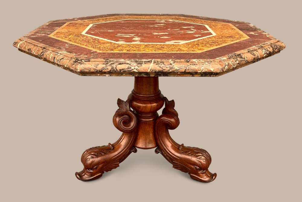An octagonal 19th-century centre table with a geometric inlaid specimen marble top supported on a carved walnut pedestal base with scroll feet. View XX