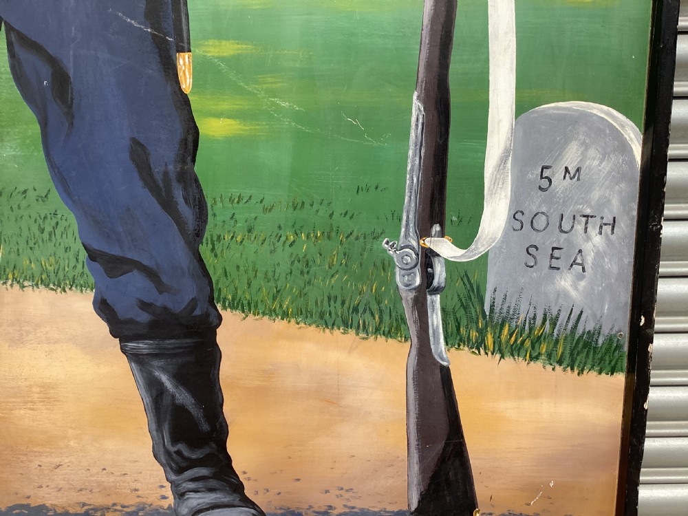 A large rectangular hand-painted panel depicting a soldier in a red tunic and blue trousers drinking from a tankard alongside military gear and text reading 5th Hants Volunteer. View X