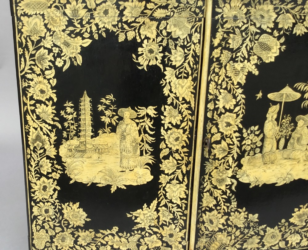 A Regency black lacquered collectors cabinet on stand featuring detailed cream and gilt Chinoiserie penwork illustrations of oriental figures and floral borders. View XX