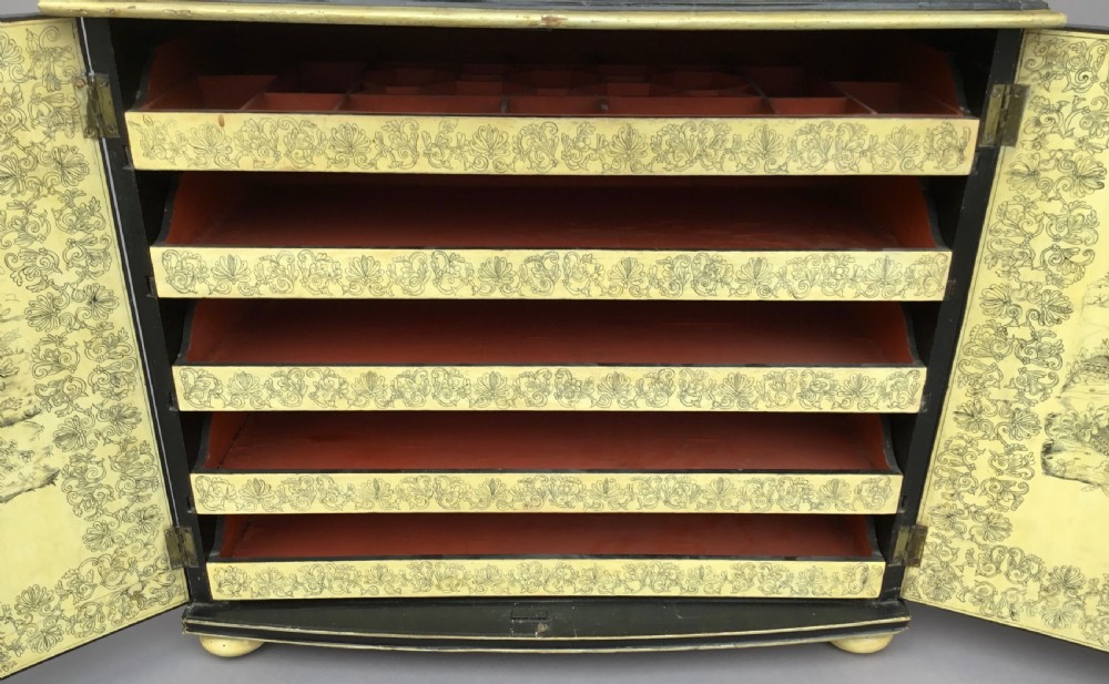 A Regency black lacquered collectors cabinet on stand featuring detailed cream and gilt Chinoiserie penwork illustrations of oriental figures and floral borders. View XXII