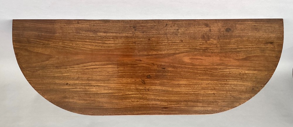 A George III mahogany demilune console table featuring a semi-circular top, plain apron, and four long square tapered legs. View XIV