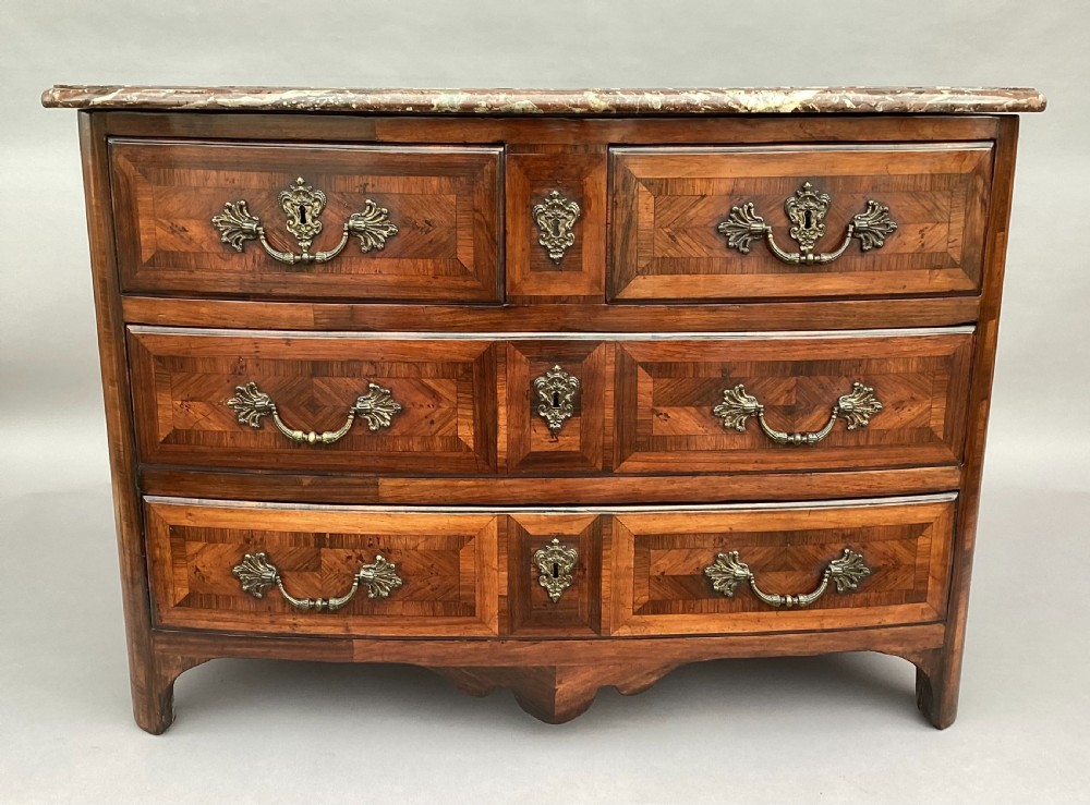 An 18th-century Louis XV bow-fronted kingwood commode featuring geometric parquetry drawers, cast bronze handles, keyhole escutcheons, and a thick marble top.