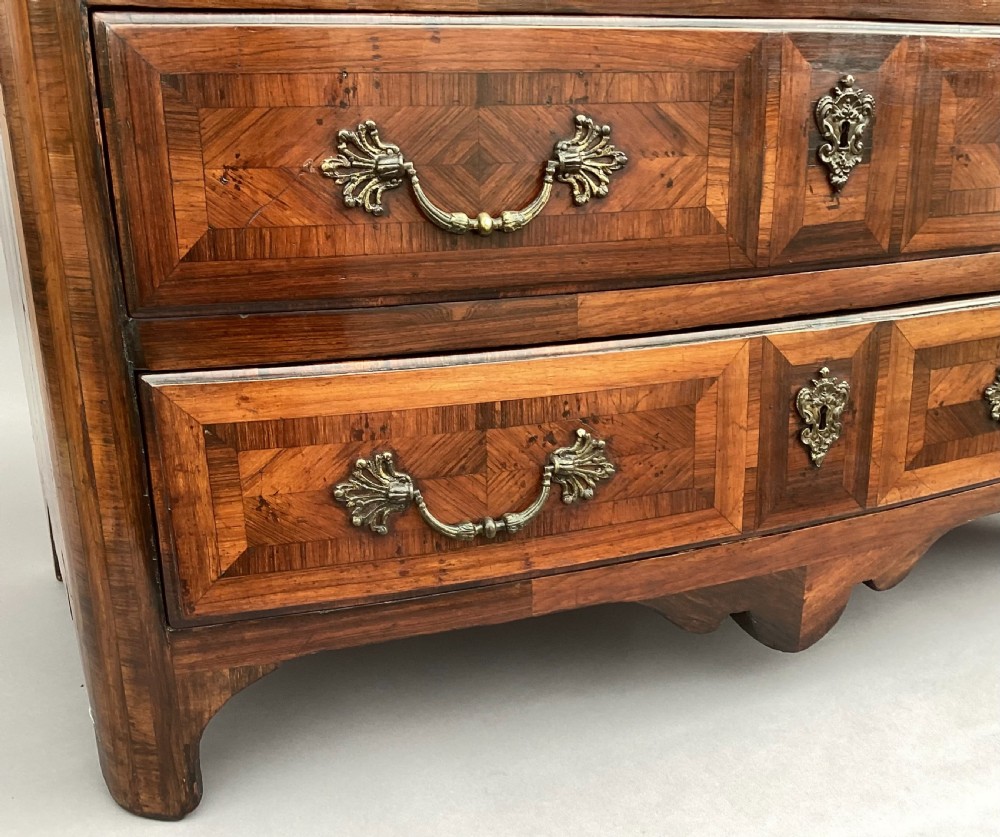 An 18th-century Louis XV bow-fronted kingwood commode featuring geometric parquetry drawers, cast bronze handles, keyhole escutcheons, and a thick marble top. View X