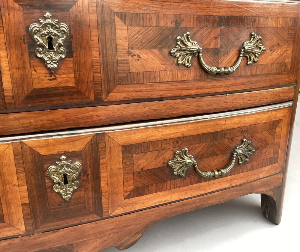 An 18th-century Louis XV bow-fronted kingwood commode featuring geometric parquetry drawers, cast bronze handles, keyhole escutcheons, and a thick marble top. View XI