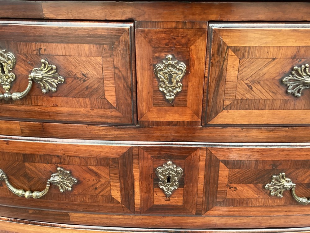 An 18th-century Louis XV bow-fronted kingwood commode featuring geometric parquetry drawers, cast bronze handles, keyhole escutcheons, and a thick marble top. View XIII